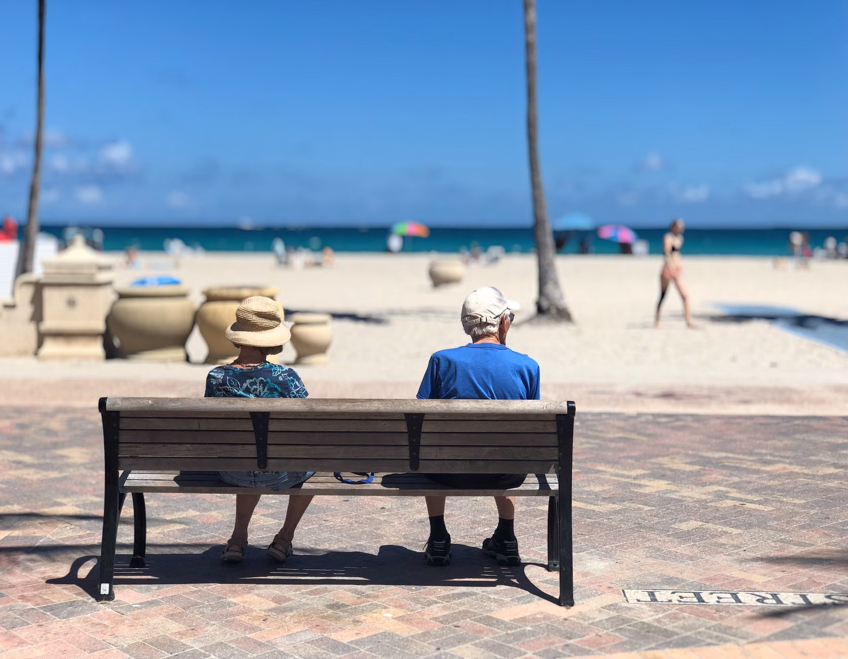 A senior couple resting on a bench in a tropical garden setting.