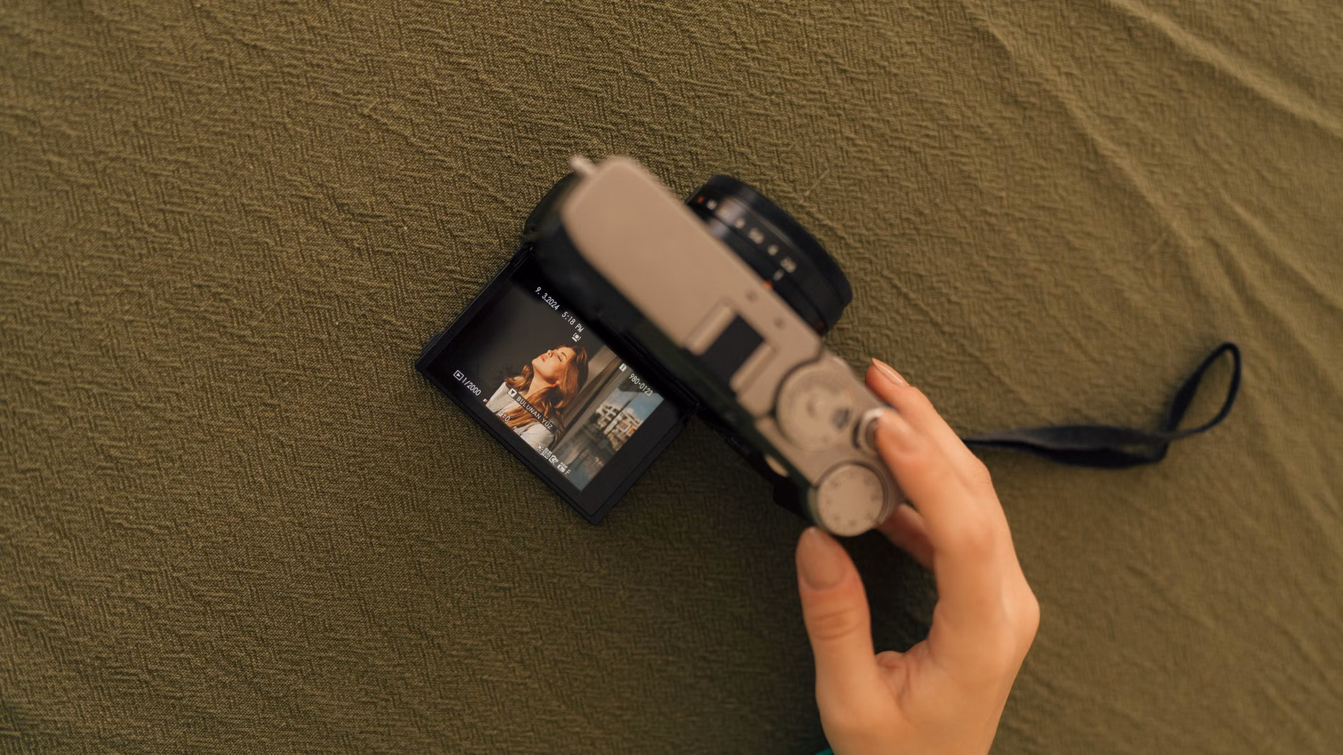 An older adult reviewing photos on a camera screen in a park.