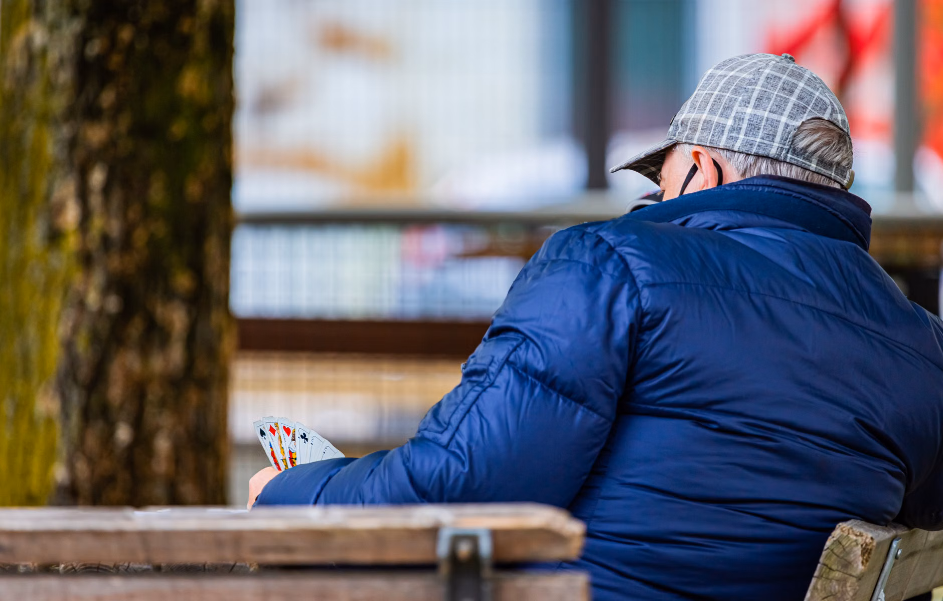 Strategy Games for Cognitive Fitness: A Practical Guide for Adults 60+ 2 Two older adults playing cards at a park bench.
