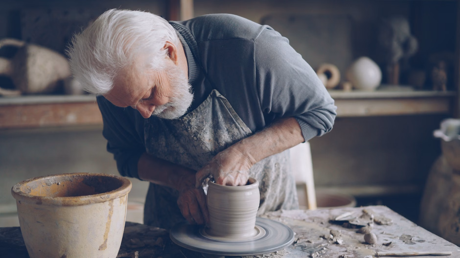 The Therapeutic Art of Pottery: A Practical Guide for Seniors 2 An older adult enjoying the process of hand-building a clay pot in a studio.