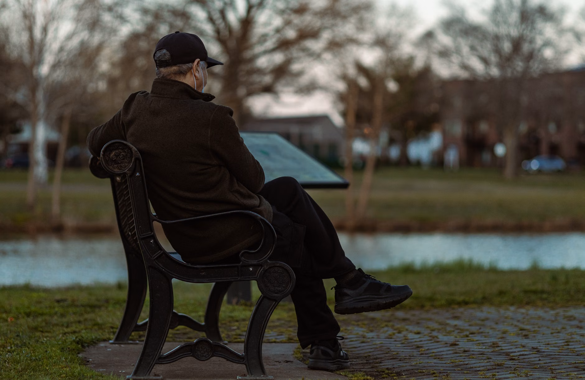 An older adult resting on a park bench while checking a mobile travel itinerary.