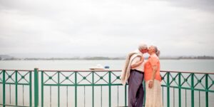 An older couple enjoying a walk on a shaded, accessible boardwalk in a tropical climate.