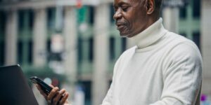 A senior adult using a smartphone at a modern, accessible transport terminal.