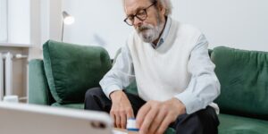 A senior adult using a tablet for digital health services in a comfortable home setting.