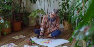 An elderly person engaging in watercolor painting in a sunlit studio.