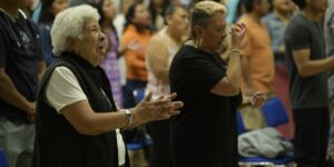 A diverse group of seniors singing together in a bright community hall.