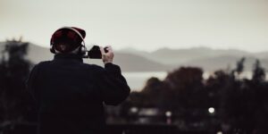 An older adult engaged in landscape photography in a scenic mountain setting.