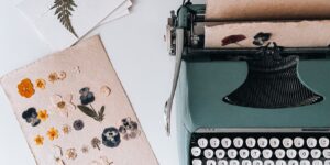 A workspace featuring a professional flower press, tweezers, and vibrant pressed flowers on a wooden table.