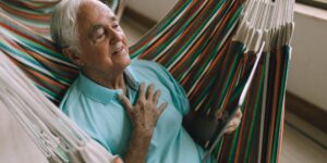 A senior adult performing a gentle seated chest-opening exercise for better posture.