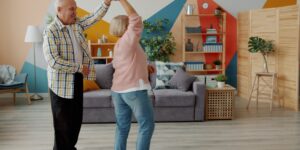 An older adult practicing hand exercises in a bright living room.