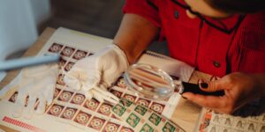 Hands using tweezers to place a stamp in a protective sleeve