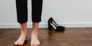 Close-up of a person's feet on a wooden floor, representing foot health and stability.