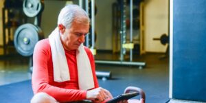 An older adult performing seated hip exercises in a bright, modern living room.