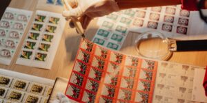 An elderly person using tweezers to place a vintage stamp into an album.
