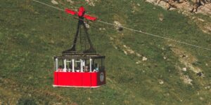 Modern cable car ascending a mountain peak.