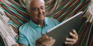 A senior adult using a tablet in a bright home office.