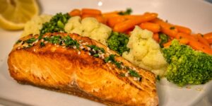 A healthy, balanced meal featuring salmon and vegetables representing good sources of Vitamin B6.
