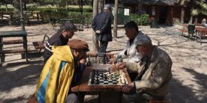A group of older adults playing chess in a well-lit community space.