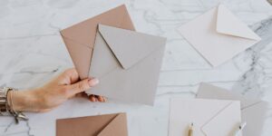 Hands holding various rustic seed envelopes at a garden table.