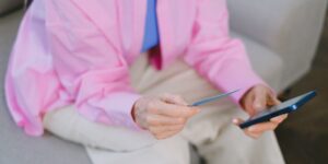 An older adult using a digital device for financial tasks in a bright, modern home office.
