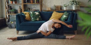 A person performing a seated side-stretch in a sunlit living room.