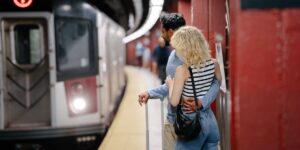 A senior couple standing on a clean train platform ready for travel with light luggage.