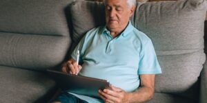 An older adult comfortably using a tablet for digital tasks at home.