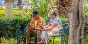 A senior couple using a smartphone for navigation in a historic European city square.