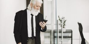 A senior person using a smartphone to navigate a modern train station.