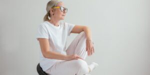 A senior adult performing seated pelvic tilts in a bright, comfortable home environment.
