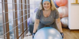 A person holding a soft exercise ball in a bright living room.