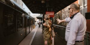 A senior couple standing on a train platform with minimal luggage, preparing for a rail journey.