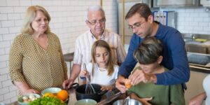 A diverse group of older adults sharing recipes and kitchen history around a dining table.