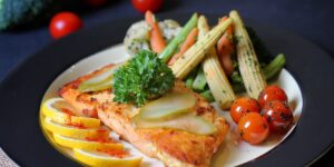 A healthy, balanced meal featuring fish and vegetables on a wooden table.