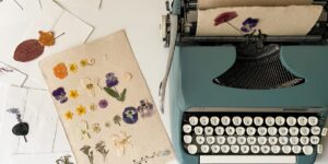 A workspace featuring a flower press, tweezers, and colorful pressed flowers on a wooden desk.