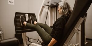 A senior adult performing a seated knee-press exercise in a home setting.