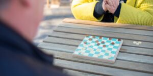 Two older adults enjoying a strategic board game in a bright, sunlit room.
