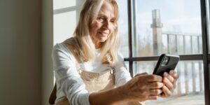A senior person using a transit app at a bright, modern bus station.
