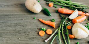 Fresh green vegetables on a wooden table representing a healthy, Vitamin K-rich diet.