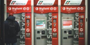 A senior traveler calmly using a digital train ticket kiosk in a modern, well-lit station.