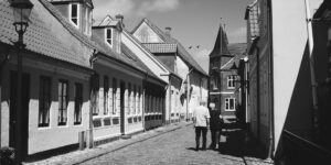 Senior couple walking through a historic European town square with cobblestones.