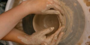 Close-up of a senior's hands working with clay on a pottery wheel.