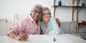 A senior couple reviewing smart home energy settings on a tablet in a well-lit living room.