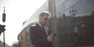 A senior traveler using a smartphone to check transport information in a modern station.
