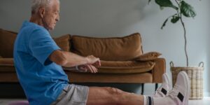 An older adult performing seated exercises in a comfortable home setting.