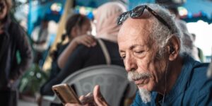 A senior traveler using a smartphone for translation at an international airport.