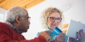 A senior couple using a tablet for digital health services in a modern, well-lit living room.