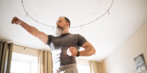 An older adult performing seated toe-tapping exercises in a bright living room.