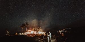 An older couple stargazing under a clear Milky Way sky with binoculars.