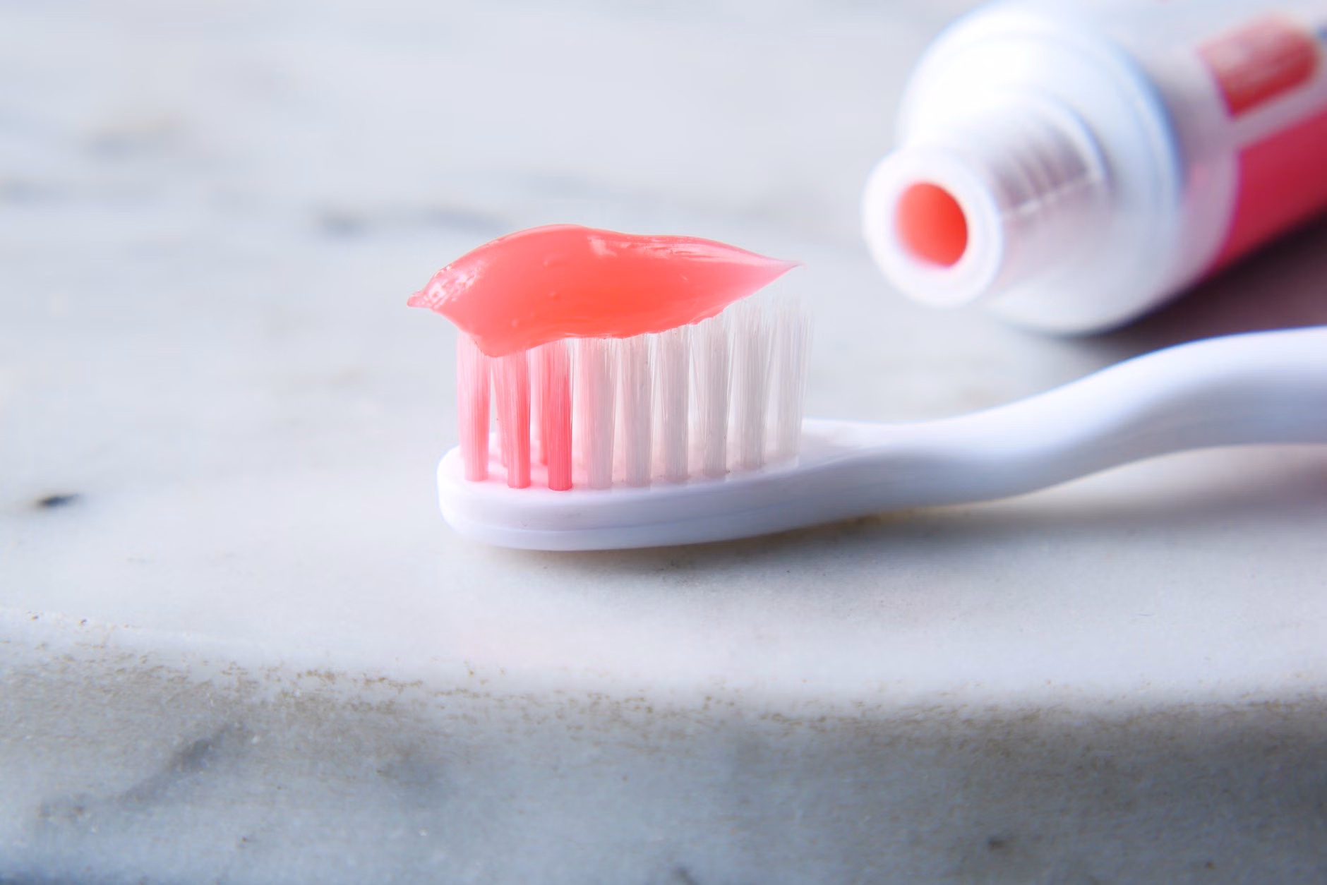 Maintaining Dental Enamel After 60: A Practical Guide to Dietary and Topical Fluoride 1 Fluoride toothpaste and a soft-bristled toothbrush on a bathroom vanity.